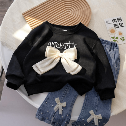 Stylish girls outfit with a modern touch - black top with stylish bowknot and attractive pleated jeans